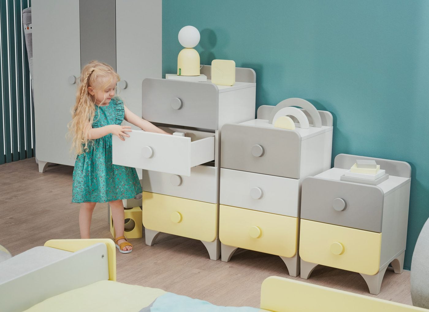 Minia Montessori kids room: a little girl opening a chest drawer by herself, low bed